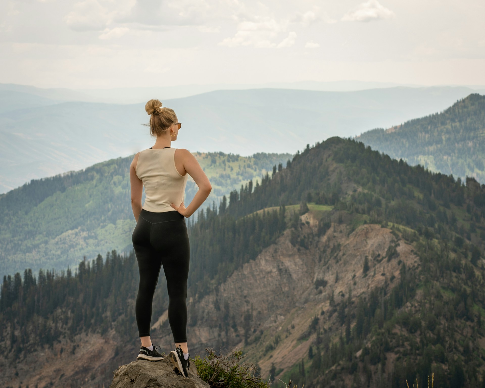 Woman standing on a mountain summit overlooking a vast landscape